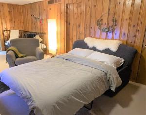 ein Bett und ein Stuhl in einem Zimmer mit Holzwänden in der Unterkunft Montreal - Laval Haven - Entire rental unit in Laval