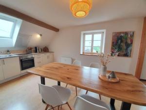 eine Küche mit einem Holztisch und weißen Stühlen in der Unterkunft Helle Ferienwohnung - Südeifel in Ammeldingen
