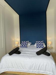a bedroom with a large white bed with a blue wall at L’esplanade du lac in Gérardmer +16 photos