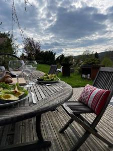 a wooden table with plates of food and wine glasses at Villa Jura, l’écrin à pied entre village et pistes in Foncine-le-Haut