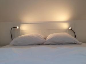 a bed with two pillows and two lights on it at Loft Sympa au calme in Sourdun