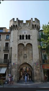 een groot stenen gebouw met een boog in een stad bij Le provençal in Manosque