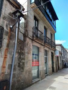 un antiguo edificio de piedra con un cartel en una ventana en Apartamentos & Rooms Santiaguiño, en Padrón