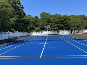 a tennis court with a blue tennis court at Sunbird Cape Cod Annex in West Yarmouth