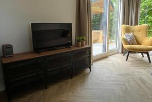 a living room with a flat screen tv and a chair at Landzicht Natuur Rust en Ruimte in Oosterwolde