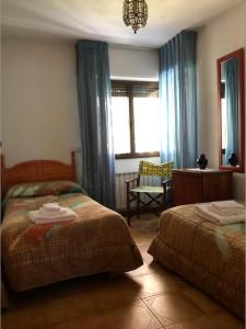 1 Schlafzimmer mit 2 Betten, einem Schreibtisch und einem Fenster in der Unterkunft Casa Pepe in Navarredonda de Gredos