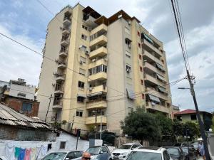 een hoog gebouw met auto's geparkeerd voor het bij City center Apartment 1 in Tirana