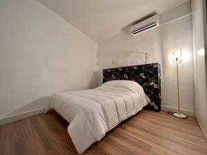 a bedroom with a bed with a white blanket and a lamp at Collioure, centre ville, joli T2 in Collioure