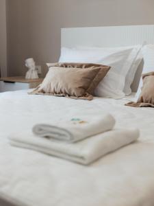 toalla blanca en cama blanca con almohadas en Five Hotel en Astaná