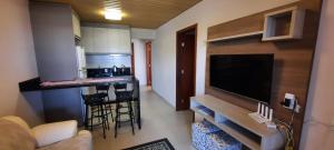 cocina y sala de estar con TV de pantalla plana grande en Apartamento Pinheira, en Palhoça