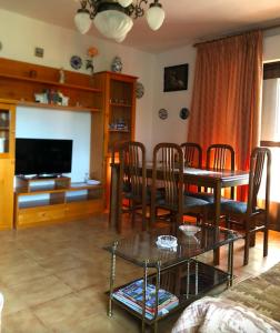 ein Wohnzimmer mit einem Tisch, Stühlen und einem TV in der Unterkunft Casa Pepe in Navarredonda de Gredos