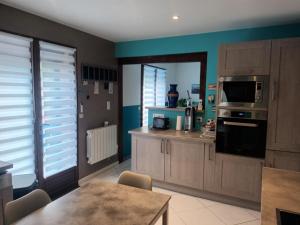 a kitchen with wooden cabinets and a table and a microwave at Au chant des mandarins 2 gites de 15 personnes et un 3ème gite à proximité de 12 in Charmes