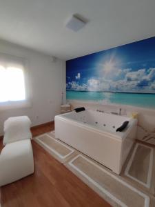 - une baignoire blanche dans une pièce ornée d'une peinture sur l'océan dans l'établissement Casa Airen con jacuzzi, à Miguel Esteban