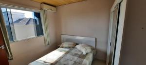 a small bedroom with a bed and a window at Apartamento Pinheira in Palhoça