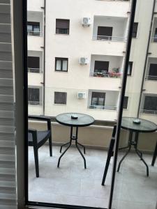 two tables and chairs on a balcony with a building at Apartman Jakov in Bečići