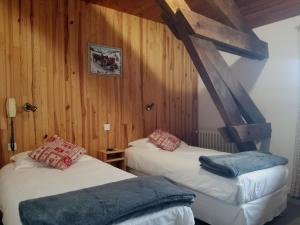 two beds in a room with wooden walls at Hôtel L'Amoulat in Gourette