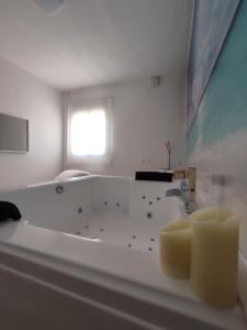 - une salle de bains blanche avec une baignoire et deux bougies dans l'établissement Casa Airen con jacuzzi, à Miguel Esteban