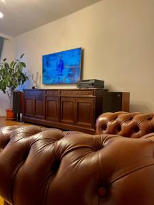 um sofá de couro castanho numa sala de estar com uma televisão de ecrã plano em Dream Home em Turda