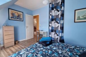 um quarto com paredes azuis, uma cama e uma secretária em Maison de famille située à Saint-Molf. em Saint-Molf