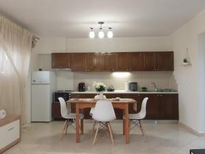 a kitchen with a wooden table and white appliances at by The Sea Apartment in Iraklitsa