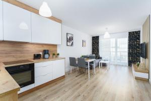 una cucina e una sala da pranzo con armadi bianchi e tavolo di Apartament D-07 "NAWIGATOR" Kołobrzeg by Holiday&Sun a Kołobrzeg