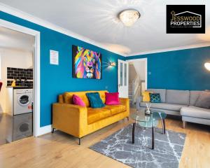 a living room with a yellow couch and blue walls at Stylish 3 Bedroom Contractor House Stevenage by Jesswood Properties Short Lets Free Parking & Wifi in Stevenage