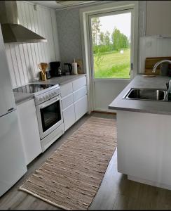 kuchnia z białymi urządzeniami i dużym oknem w obiekcie Litet hus på landet 