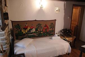 1 dormitorio con 1 cama con una pintura en la pared en ΤΑ ΚΩΝΣΤΑΝΤΑΔΙΚΑ, en Arnaia
