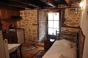 a bedroom with a bed and a kitchen with a window at ΤΑ ΚΩΝΣΤΑΝΤΑΔΙΚΑ in Arnaia