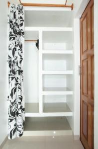 a walk in closet with white shelves and a door at eco trekking lodge Bar & tour's in Bukit Lawang