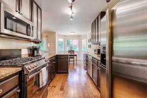 uma cozinha com um frigorífico em aço inoxidável e pisos em madeira em Spacious Oasis Hot Tub Backyard Garden 3BR/2BA em Sonoma