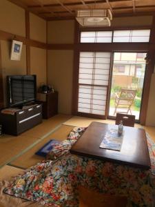 Tomato House في Funehiki: غرفة معيشة مع طاولة قهوة وتلفزيون