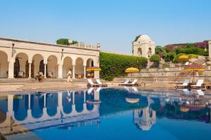 una piscina de agua con sillas y un edificio en The Oberoi Amarvilas Agra en Agra