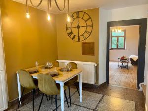 a dining room with a table and a clock on the wall at Le Sartisfait in Jalhay