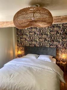 1 dormitorio con 1 cama grande y lámpara de araña grande en Le Sartisfait en Jalhay