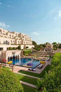 a large building with a swimming pool with umbrellas at The Oberoi Amarvilas Agra in Agra
