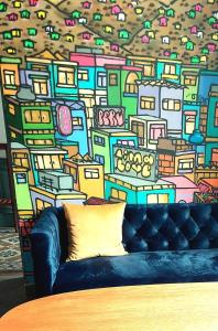 a couch in front of a wall with a painting at 1900 Hostel in Lima