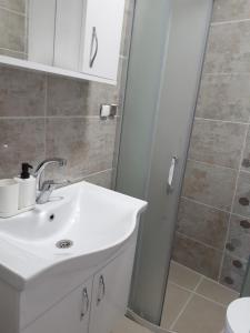 een badkamer met een witte wastafel en een douche bij OTELIA PANSIYON in Ayvalık