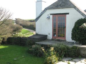 a small white house with a red door at Church Cottage in Bude +2 photos