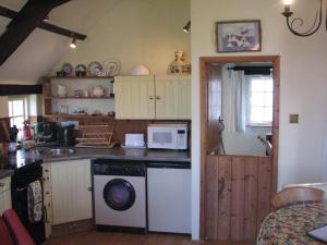 a kitchen with a dishwasher and a microwave in it at Church Cottage in Bude