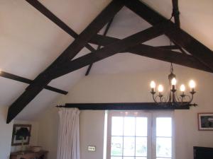 a room with wooden beams and a window and a chandelier at Church Cottage in Bude