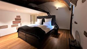 um quarto com uma grande cama preta e almofadas brancas em Historical Luxury Homes - Luxus Familien Suite em Friburgo em Brisgóvia