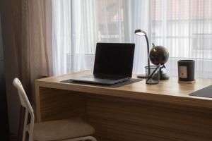 a laptop computer sitting on a wooden desk with a window at Modernes Studio mit großem Balkon, vollausgestatteter Küche und idealem Arbeitsplatz für Home Office in Gärtringen