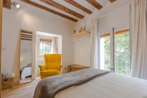 a bedroom with a bed and a yellow chair at DuermeCuenca in Cuenca