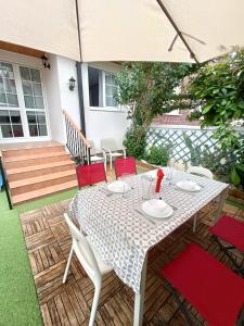 una mesa con sillas rojas y una sombrilla en el patio en Paraíso Soleado: Piso con Terraza, Piscina y Garaje a 5 min de Playa, en Castro Urdiales