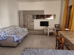 ein Wohnzimmer mit einem Sofa und einem TV in der Unterkunft Tramonto Apartment Seaview in Santa Domenica