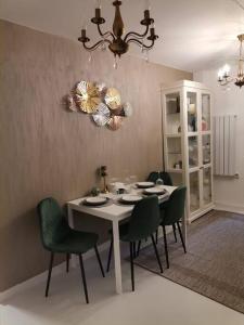 a dining room with a white table and green chairs at Herastau Apartment in Bucharest