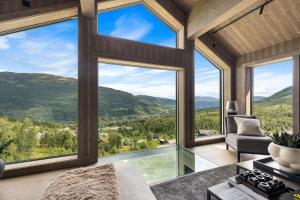 um quarto com grandes janelas com vista para as montanhas em The Panorama Retreat - Rindabotn Cabin em Sogndal