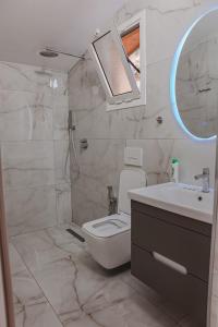 La salle de bains est pourvue de toilettes, d'un lavabo et d'un miroir. dans l'établissement Plazhi Gjeneralit - Small Cabins - Bungalows - Apartaments - Villas - Suite, à Kavajë