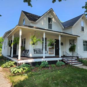een wit huis met een veranda met een bankje erop bij The Landerholm Bed and Breakfast in Wisconsin Rapids